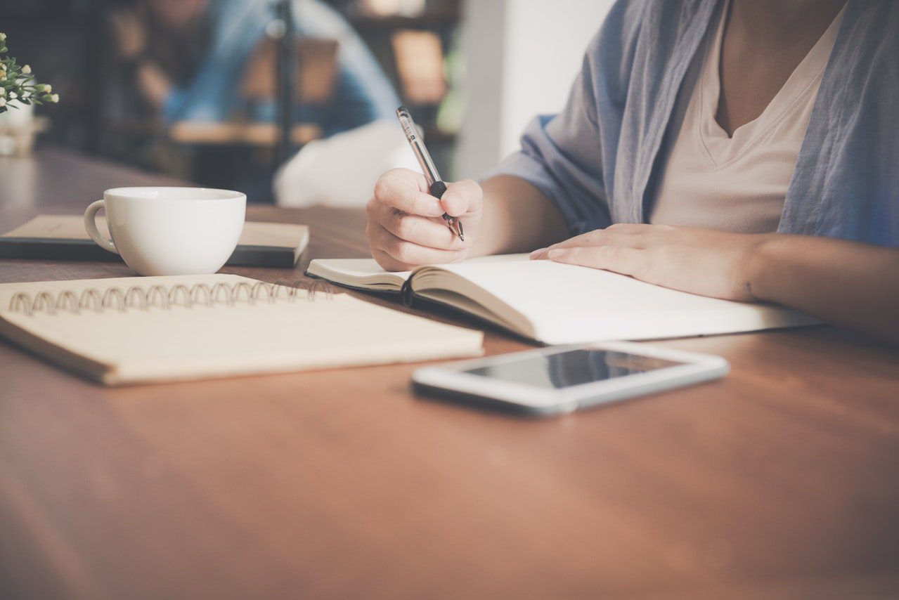 Person writing in a notebook at a desk