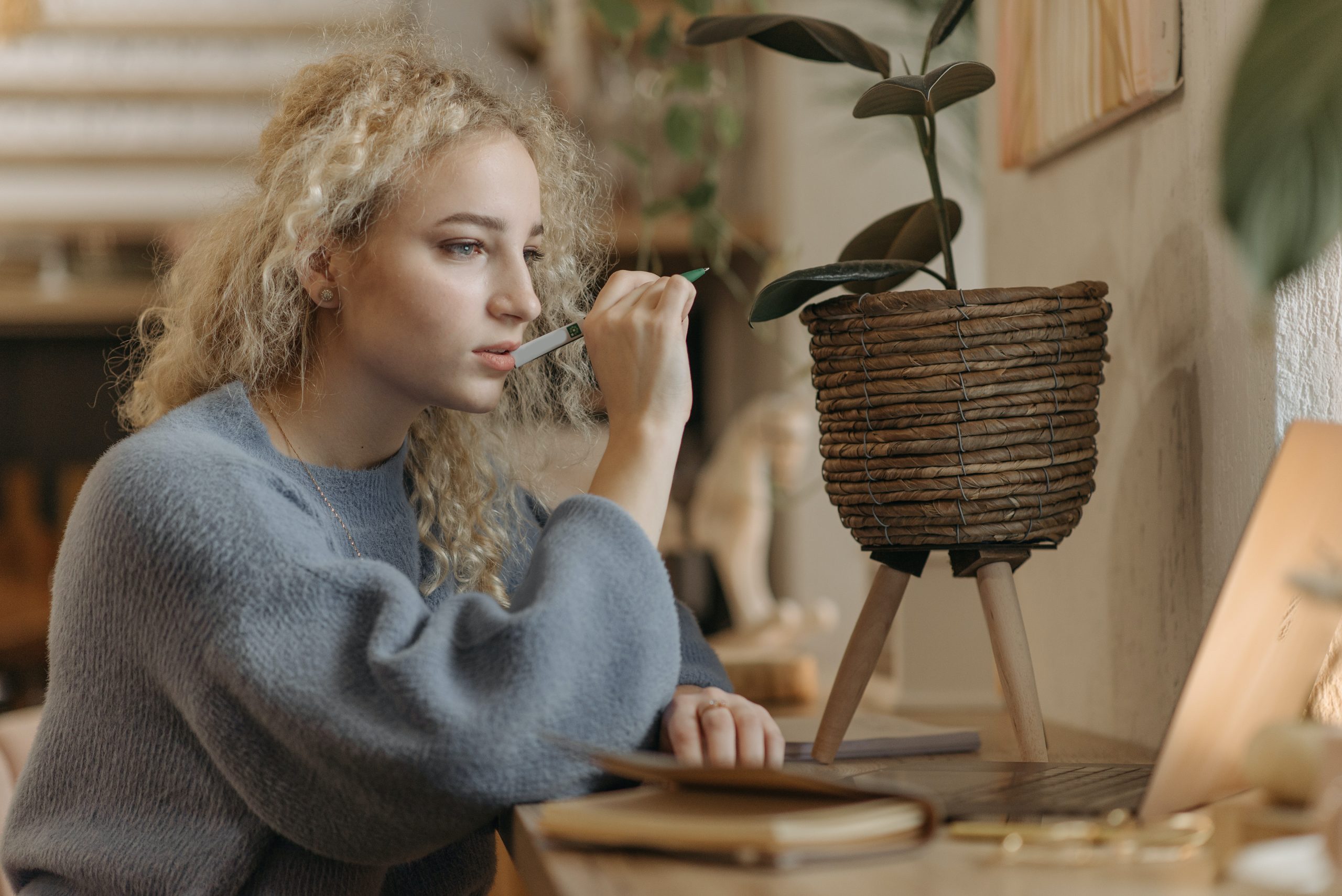 Do I need a website if I have a Facebook page - Woman in blue sweater thinking and looking at laptop