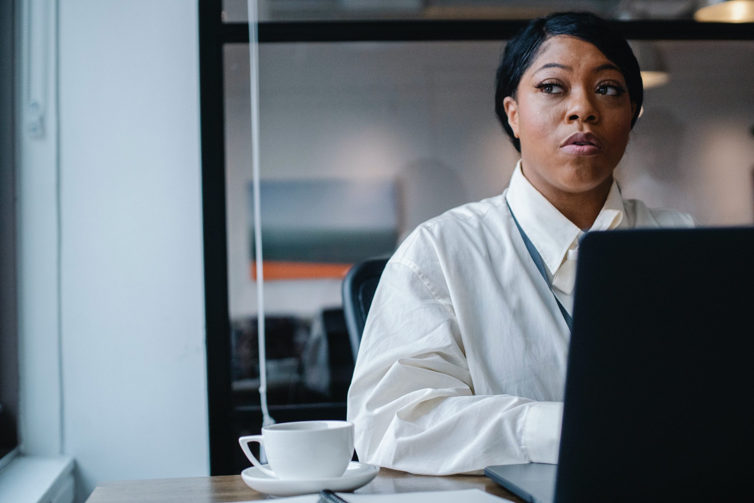 Woman looking thoughtful at a laptop