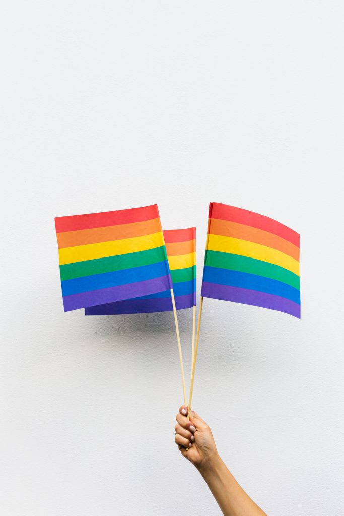 Hand holding multiple rainbow flags representing diversity