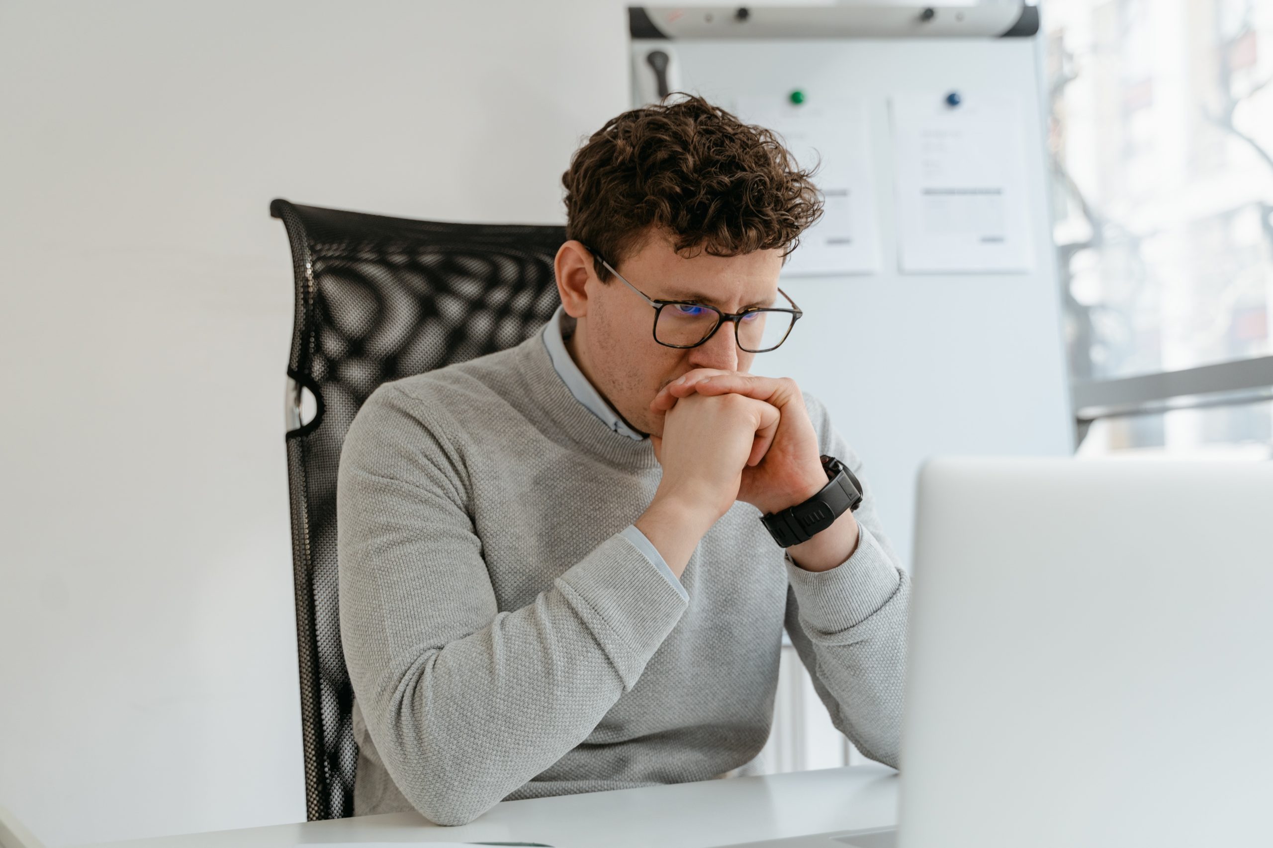 Man looking serious at his computer considering app purchase