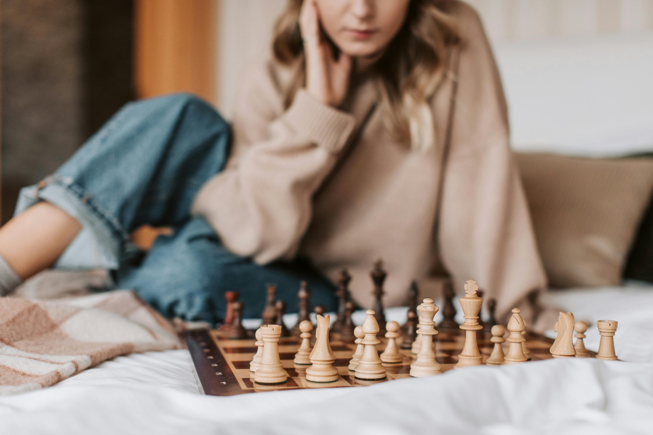 Woman contemplating next strategic move on a chessboard representing multiple businesses.