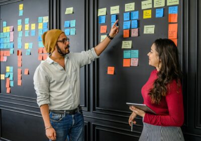 Work colleagues discussing consistency using post-it notes on a wall