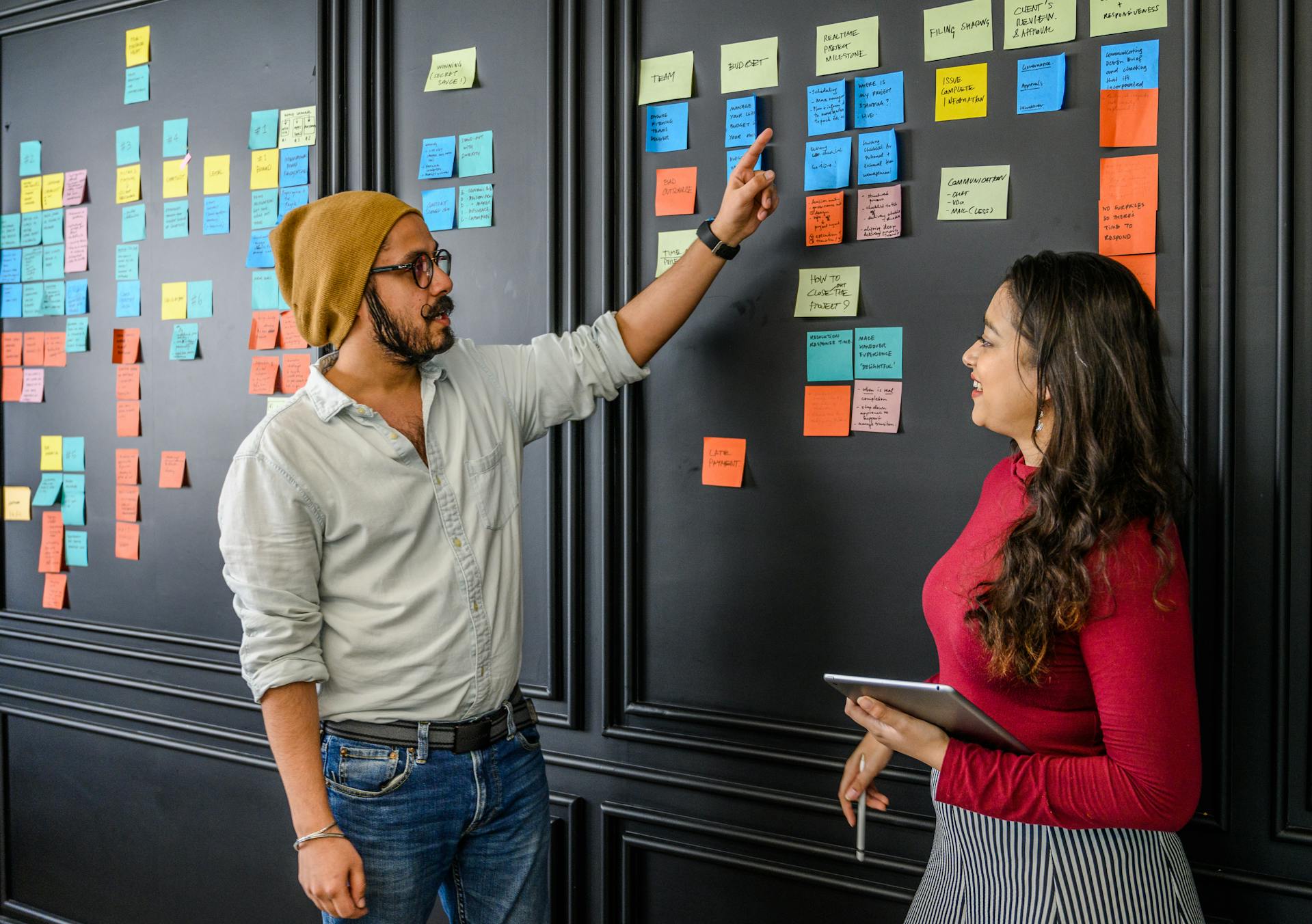 Work colleagues discussing consistency using post-it notes on a wall