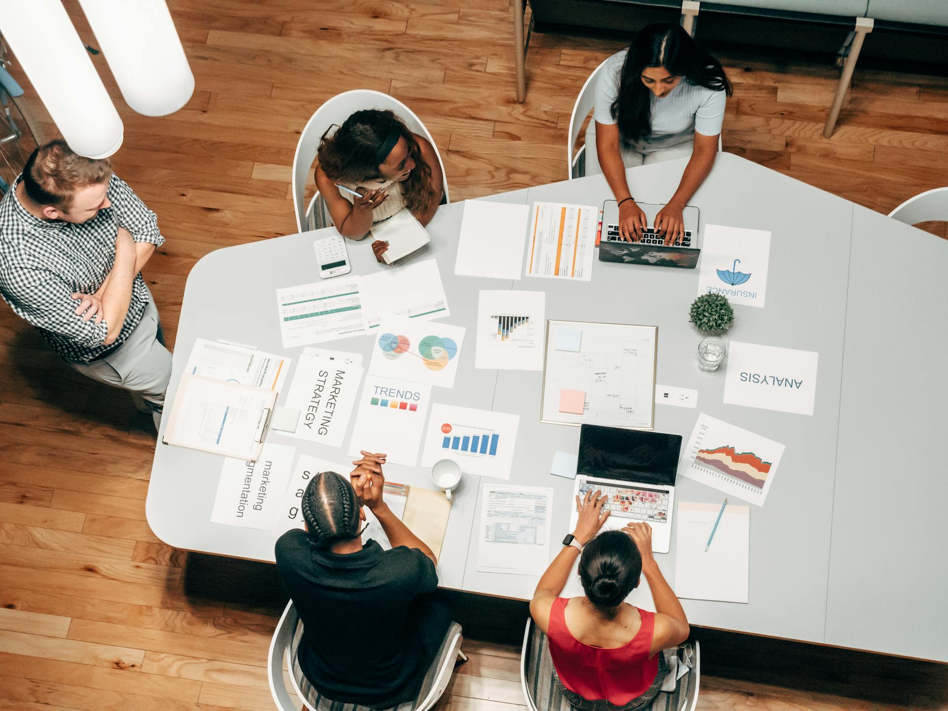 5 people working around a large table covered with marketing strategy and data.
