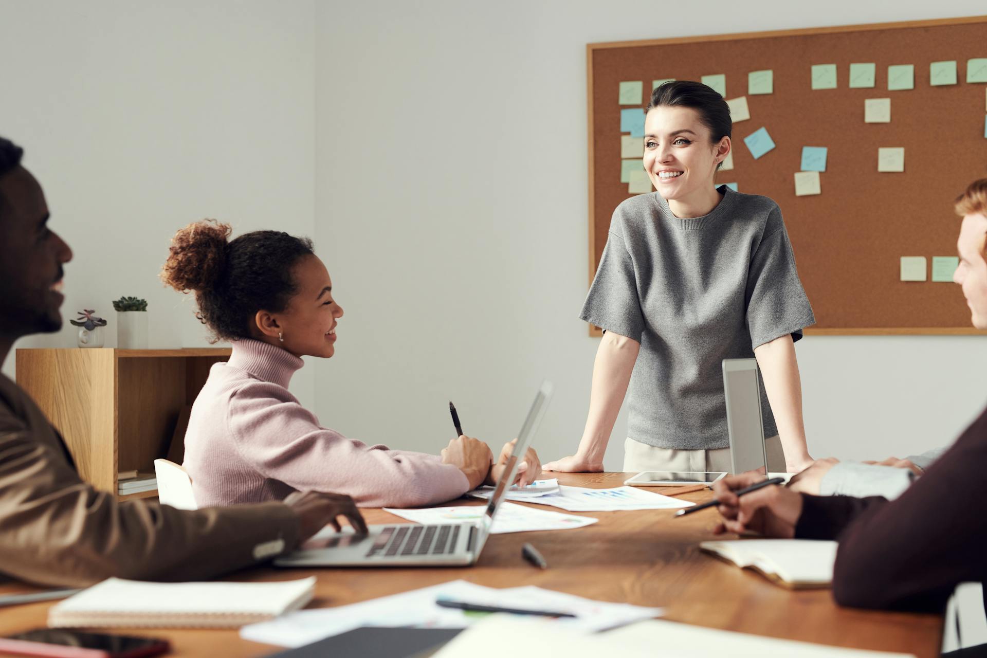 Excited-looking business meeting around a desk with computers.