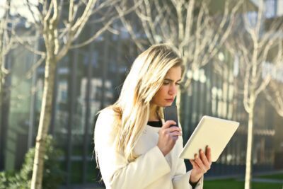 Woman looking at a tablet computer deep in thought in an outdoor setting.